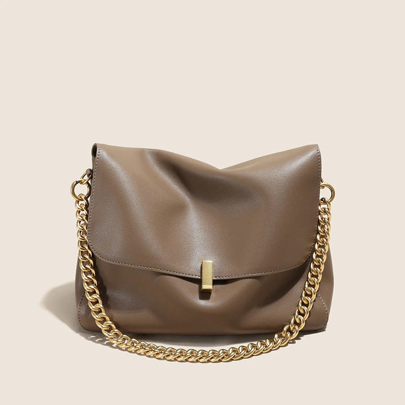 Brown leather handbag with a gold chain on a beige background