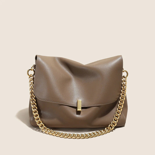 Brown leather handbag with a gold chain on a beige background